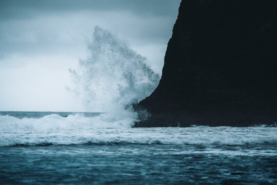 View of dramatic waves crashing on a black sand beach with rocky cliffs under an overcast sky, Playa de Benijo, Santa Cruz de Tenerife, Spain. - Powered by Adobe