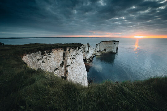 View of dramatic cliffs and serene sea at sunset with picturesque sky, Studland, England, UK.