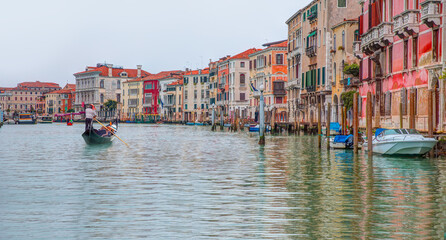 Venetian gondolier punting gondola through green canal waters of Venice Italy