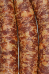 A close-up, top-down shot of three raw sausages arranged vertically, highlighting their marbled texture and natural casing