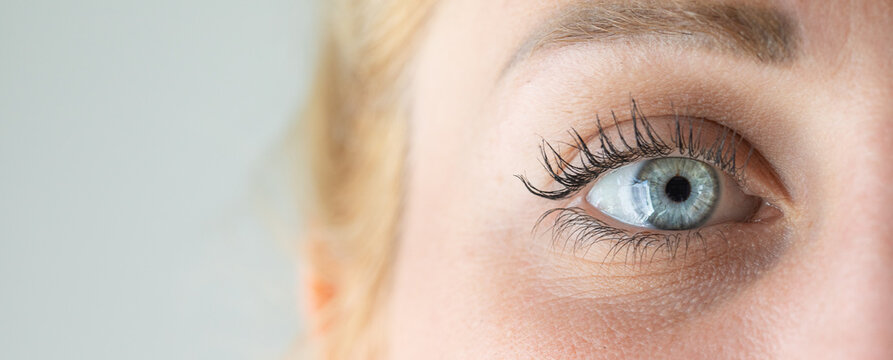 Woman showing beautiful blue eye with long black eyelashes and defined eyebrow