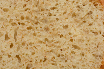 A close-up shot of a slice of homemade bread with sunflower seeds, showcasing its porous texture and natural color