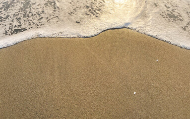 Black Sea waves and sandy beach with water during sunset or sunrise.