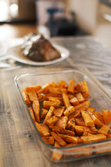 Sweet potatoes with rosemary in a glass bowl, standing on a wooden table