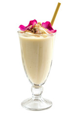 Milk smoothie with rose petals and nuts in a glass, isolated on a white background