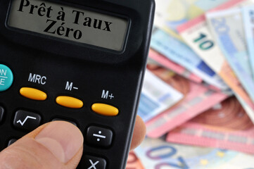 Concept de prêt à taux zéro avec une calculatrice et un fond de billets de banque flou au second...