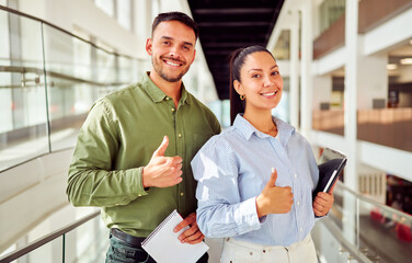 Smiling business man and woman showing thumbs up gesture of approval and success in modern office...