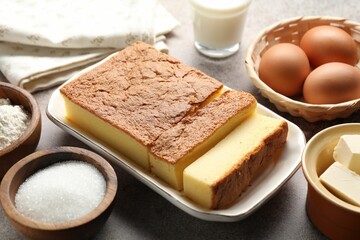 Tasty Japanese Castella sponge cake and ingredients on light table, closeup