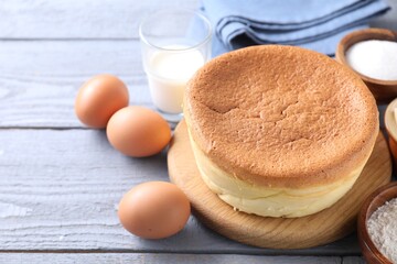 Tasty Japanese Castella sponge cake and ingredients on grey wooden table, closeup. Space for text