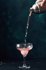 Male hand pour cocktail or mocktail into cocktail glass. Alcoholic soft drink in nightclub