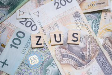 The word "ZUS" (Polish Social Insurance Institution) on a background of Polish banknotes, symbolizing social security, public funds, and financial obligations in Poland
