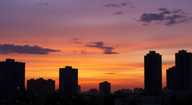 A peaceful sunset in the city, with skyscrapers silhouetted against a colorful sky.