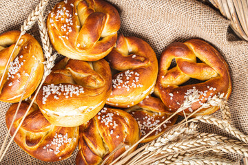 Pretzels with coarse salt. on canvas in a wicker basket with ears of wheat.