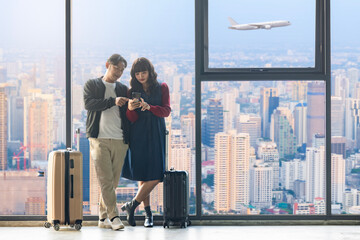 Happy Loving couple with suitcase using smartphone at home or hotel, online check-in in airline's mobile app or on the company's website for self-registration for quick access to flight at airport.