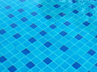 The rippling water in the pool gives the floor wavy appearance. Ripple water in blue pool. The pool is tiled with blue ceramic tiles. Blue water serface. Blue ocean rippled water texture reflection
