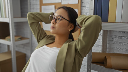 Chinese woman relaxing in an office, surrounded by books and documents, portraying a calm and professional workspace.