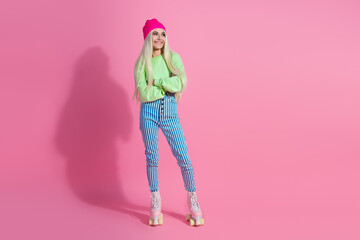 Young stylish woman in bright casual fashion wear standing on pink background, smiling happily, embodying trendy hipster charm