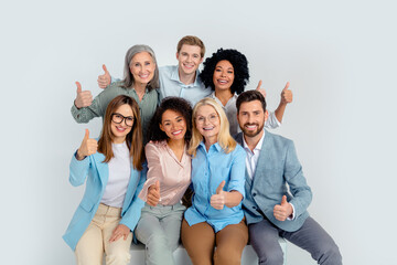 Multigenerational diverse group of professionals showing camaraderie with thumbs up in an office setting