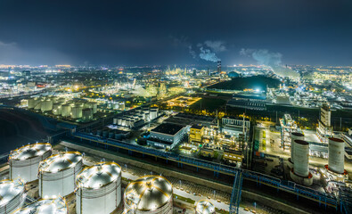 Fototapeta premium Aerial view of illuminated oil refinery plant at night time
