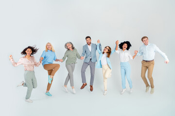 Obraz premium Diverse group of professional colleagues in formalwear smiling and celebrating together standing on light grey background