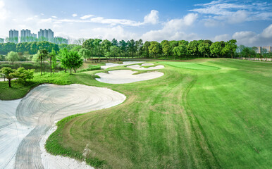 Scenic view of a green golf course with sand traps and trees