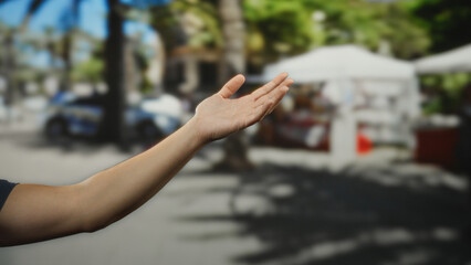 Man's hand gestures openly on a lively city street, highlighting a vibrant outdoor scene bustling...