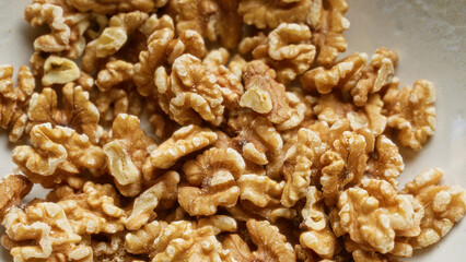 Closeup photograph of shelled walnuts clustered together in a bowl capturing detailed textures