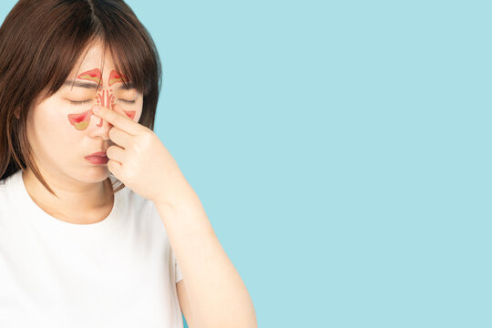 Asian woman suffering from sinusitis with nasal congestion of mucus or pus over blue background. Causes of rhinosinusitis include bacterial infections, viral infections and allergies.