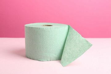 Green toilet paper roll on pink background