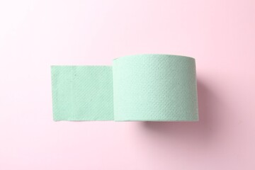Green toilet paper roll on light pink background, top view