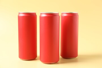 Red aluminium cans of beverage on pale yellow background