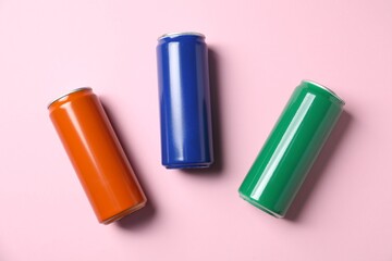Three tin cans on light pink background, flat lay