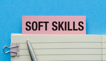 Soft Skills text concept write on pink sticker with notebook on blue background