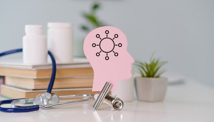 A pink head with a brain and a bunch of books on a table