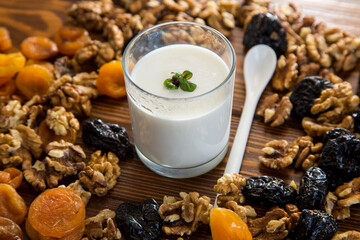 natural yogurt with nuts, dried apricots and prunes on a wooden table