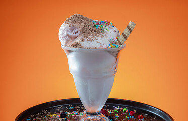 ice cream with berries in a glass on a wooden table and orange background
