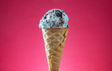Ice cream cone with colorful sprinkles on pink background, close up