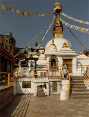 A gold and white painted Stupor adhorned with Prayer Flags