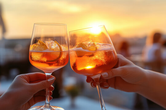 Friends clink glasses filled with vibrant drinks as a stunning sunset fills the sky