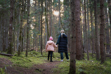 Mother and daughter in a spruce forest before sunset on an autumn day, Nature of Latvia.