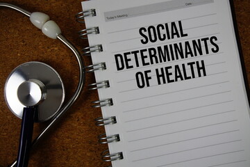 Social Determinants Of Health text on paper with stethoscope flat lay on cork board background