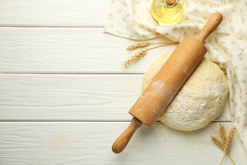 Fresh dough, rolling pin, oil and spikes on white wooden table, flat lay. Space for text
