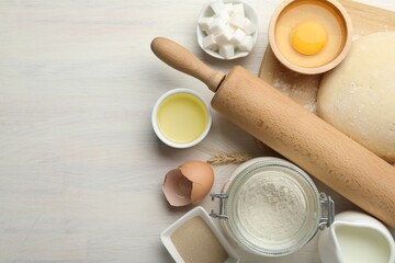 Rolling pin and different ingredients on light wooden table, flat lay. Space for text