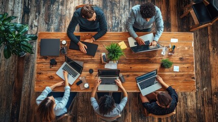 Teamwork, Collaboration, and Modern Office Space: Aerial View of Diverse Professionals Working Together on Laptops at a Rustic Wooden Table