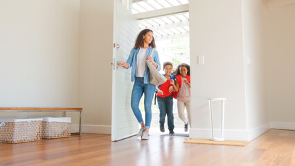 Mother And Children Opening Front Door Returning Home After School Day