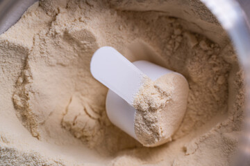 A scoop in a jar of protein powder, close-up. Sports nutrition for athletes, an additional source of protein.
