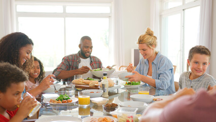 Two Families Sitting Around Table Together Enjoying Meal At Home
