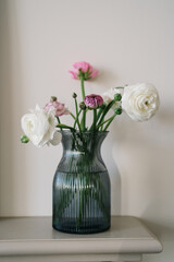 Bouquet of pink and white ranunculus flowers in a glass blue vase