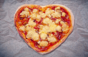 Heart-shaped pizza with tomato sauce isolated on gray background.