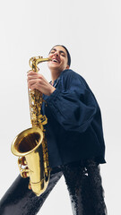 Obraz premium Joyful musician holding saxophone with broad smile, embracing moment of artistic passion against white studio background. Concept of music, joy, festival, talent, passion, performance.